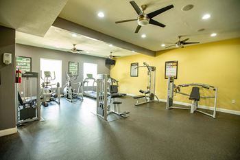 A gym with a variety of equipment including weights and cardio machines at Willow Creek Apartments, Houston, TX, 77012